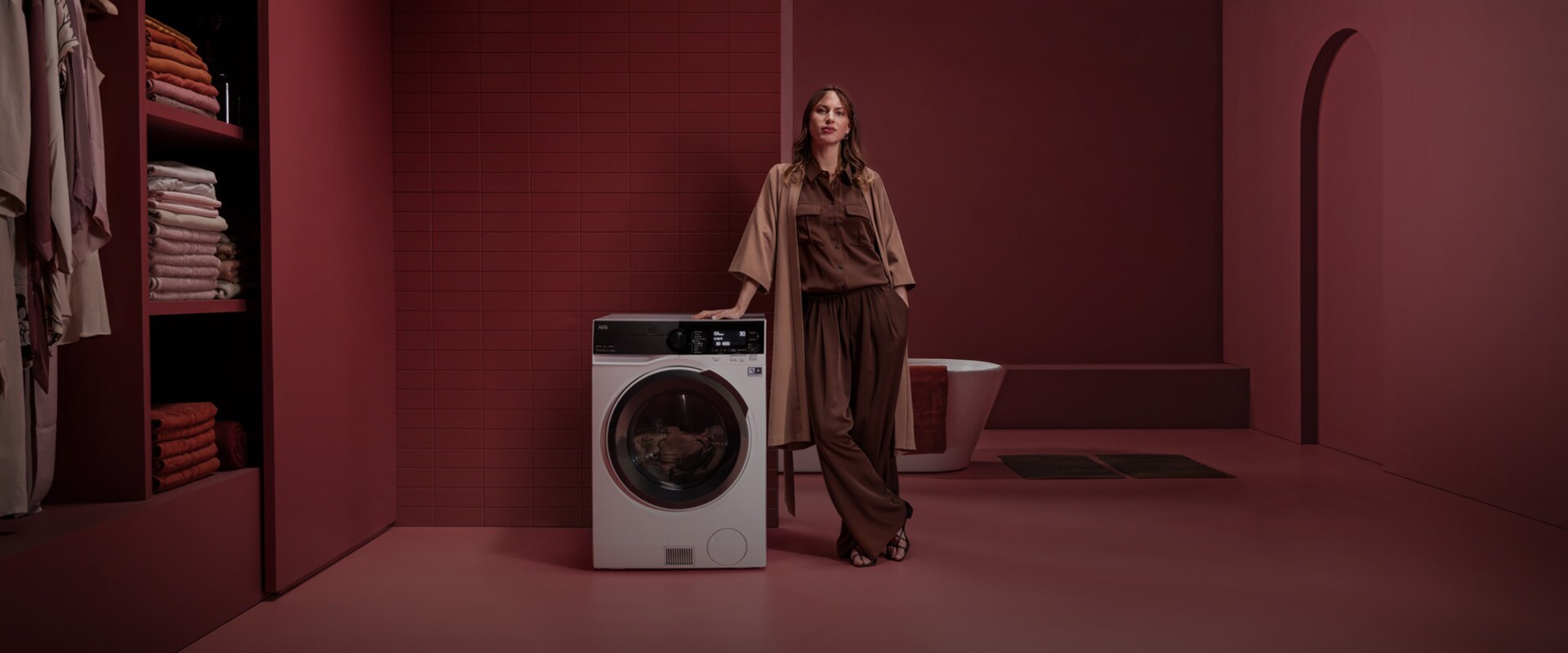 Nainen seisoo vapaasti sijoitettavan kuivaavan pesukoneen vieressä punaisessa huoneessa.